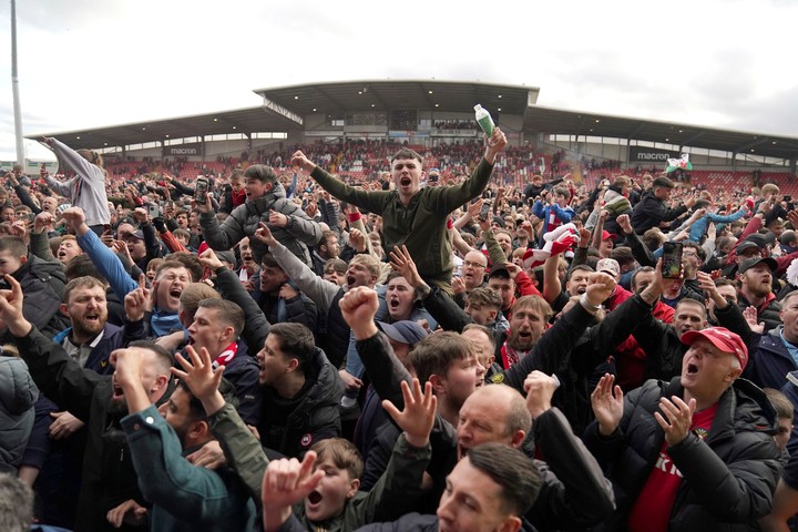 Los hinchas del Wrexham celebran el ascenso en el campo de juego. (AP)