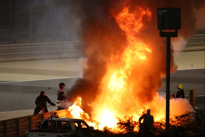 Asistentes de la FIA intentando controlar el fuego que desprendía el Haas de Romain Grosjean. (Photo by Bryn Lennon / POOL / AFP)