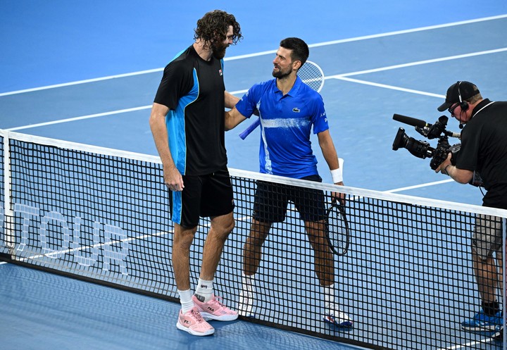 Novak Djokovic junto a Reilly Opelka en la red luego del último punto del encuentro. (EFE/EPA/DARREN)