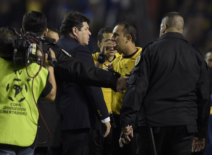 Roger Bello junto al árbitro, Darío Herrera. (AFP)