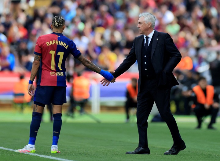 Tras la derrota de Real Madrid ante Barcelona el domingo pasado, Carlo Ancelotti saluda a Raphinha, a quien dirigirá en el seleccionado brasileño. Foto: Nacho Doce / Reuters.